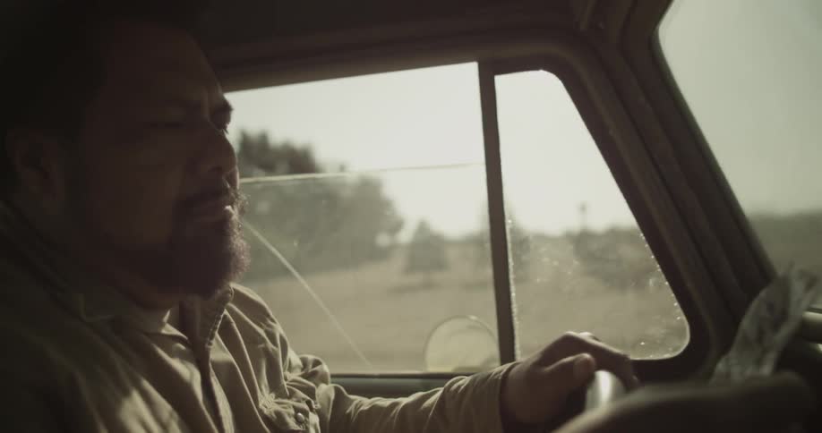 A man takes something out of his pocket as he's driving