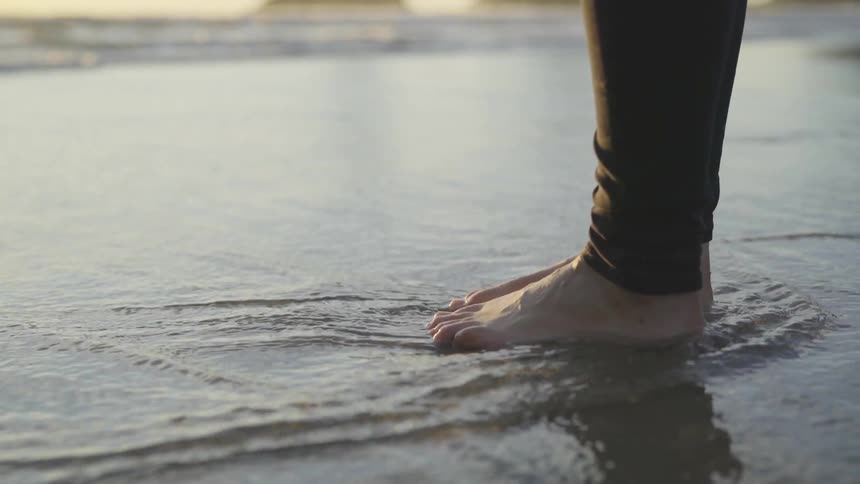 A man standing at the edge of the ocean