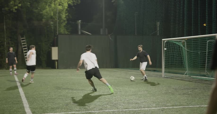 A person kicks a soccer ball to another person