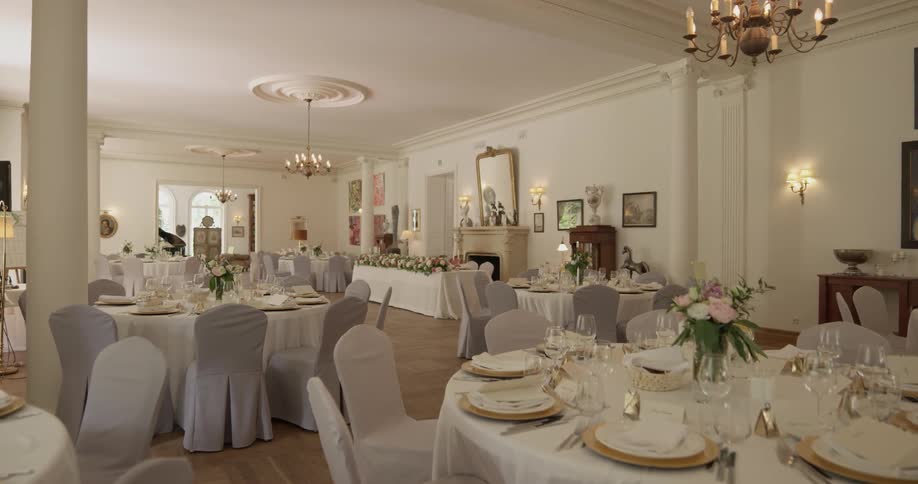 Dining tables are set and decorated in a reception hall