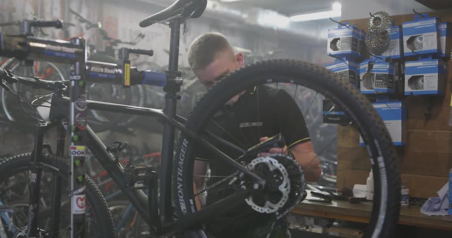 Man turns a bike tire as he examines it in a shop