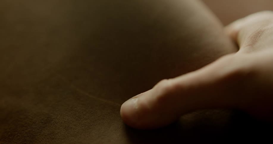 A person slides their hand over a piece of leather