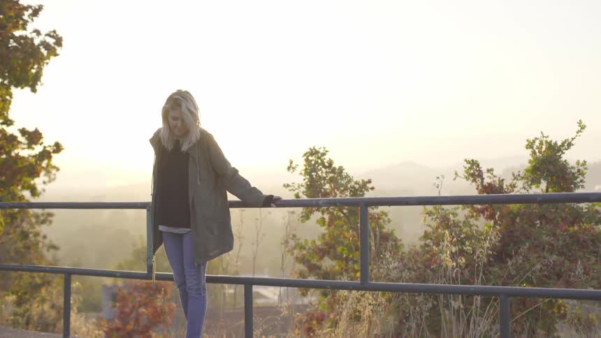 A woman standing against a railing in a park
