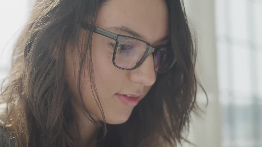 A woman with glasses is watching something in front of her