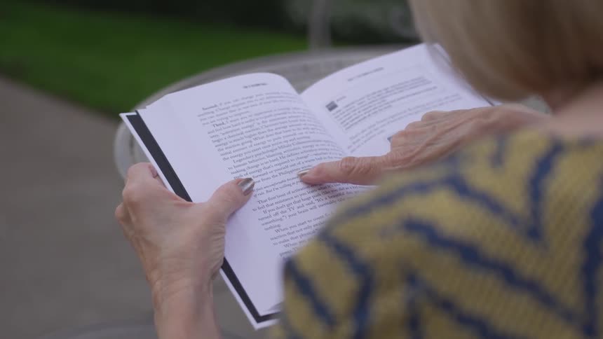 A woman using her finger to trace along the lines in a book