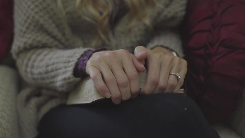 A woman wearing a ring is sitting down