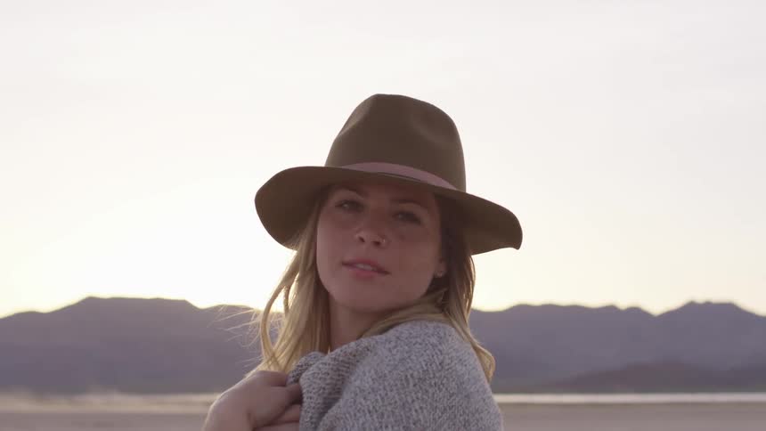 Woman in hat stands on plain with mountain on the horizon