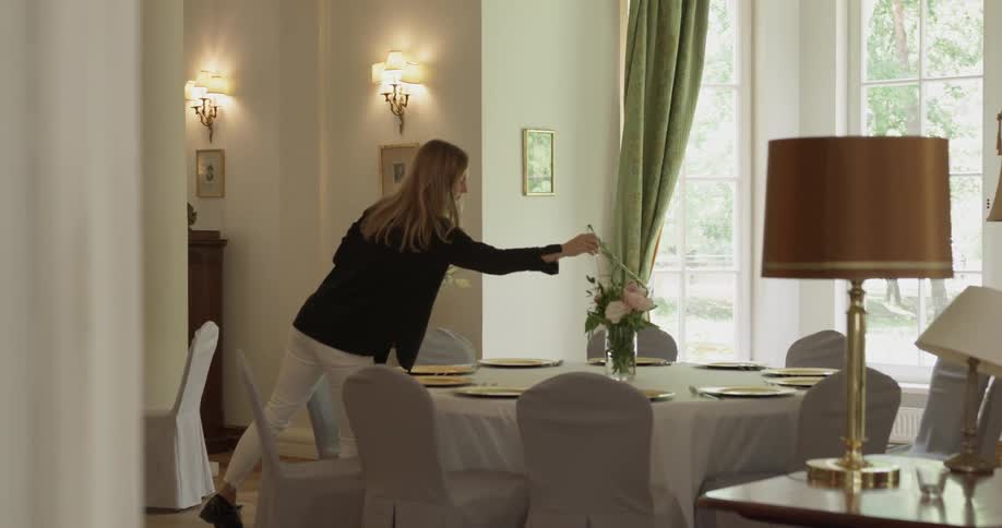 A woman places something into a flower vase