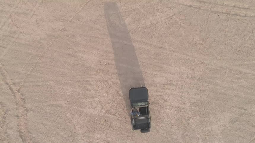 A truck driving across a dry lake bed
