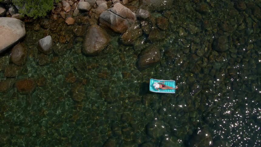 Woman Sunbathing On Raft In Water