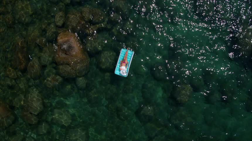 Woman Sunbathing On Raft In Water