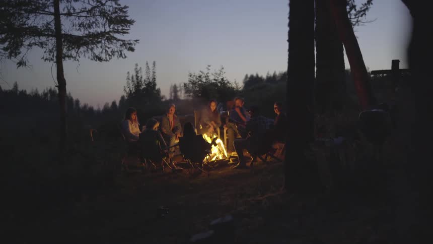 A group of people are gathered around a fire in a wilderness area
