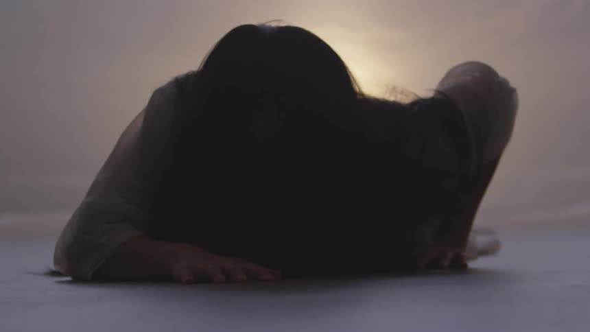 Woman crawls on the ground at sunset