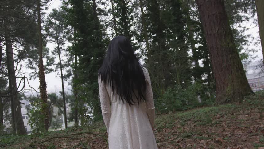 A woman standing alone in a wooded area