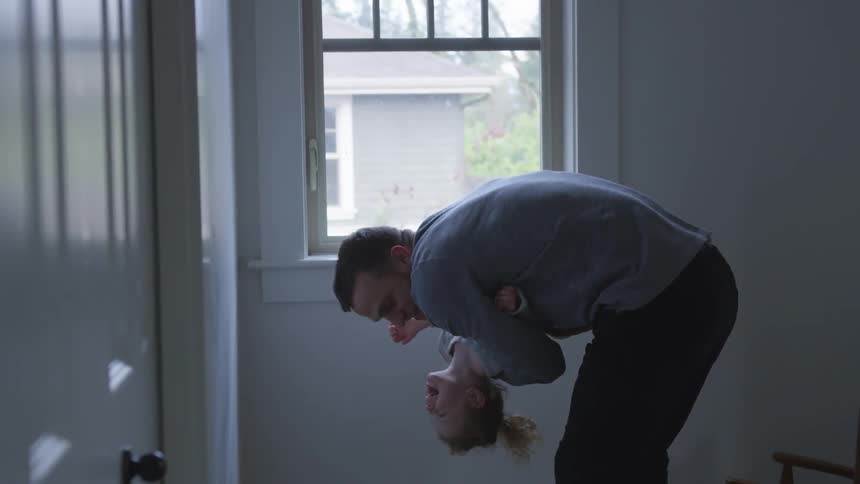 A man holding his daughter in his arms playing with her