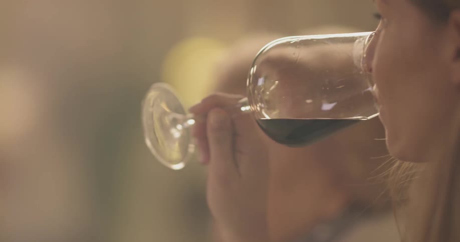 A person spins a wine glass and takes a sip