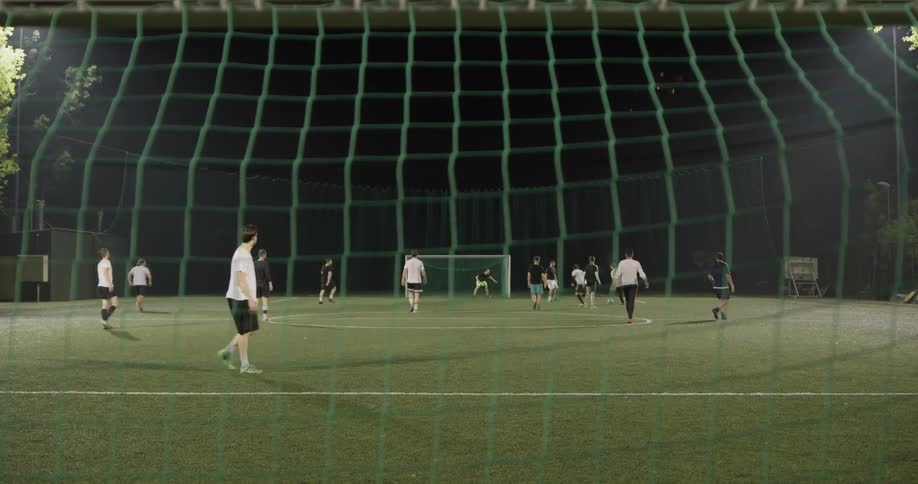 A group of people playing soccer at night