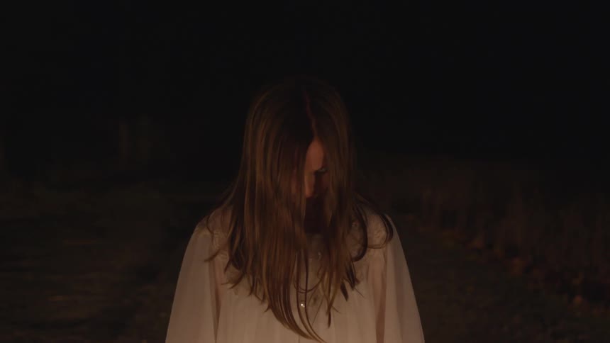 A woman standing in front of a fire outdoors
