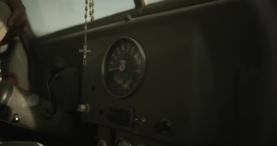 A rosary hanging from a car windshield mirror