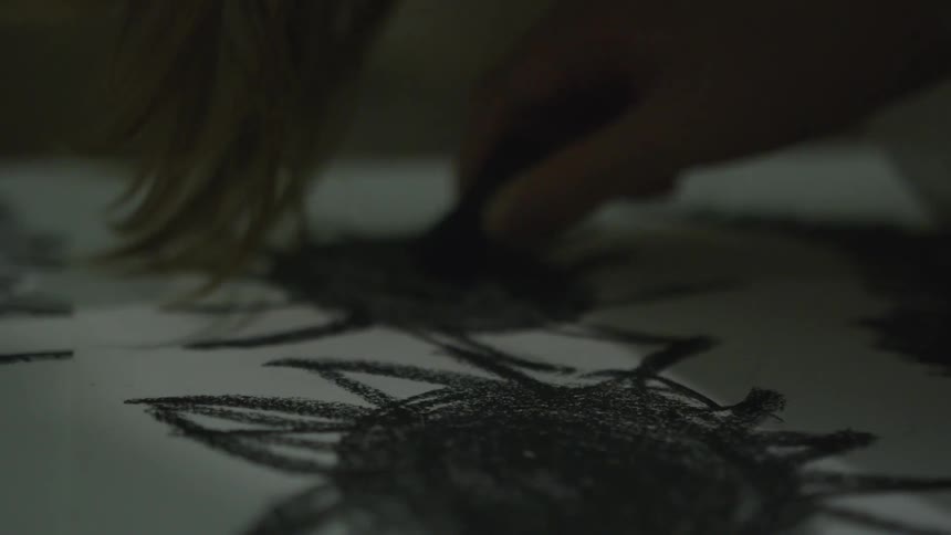 A person drawing on paper with charcoal