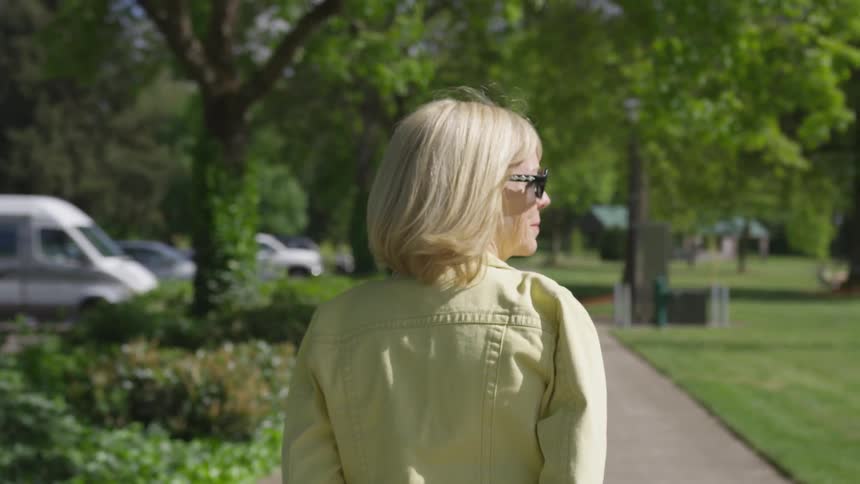 A woman walking down a sidewalk and the wind blows her hair