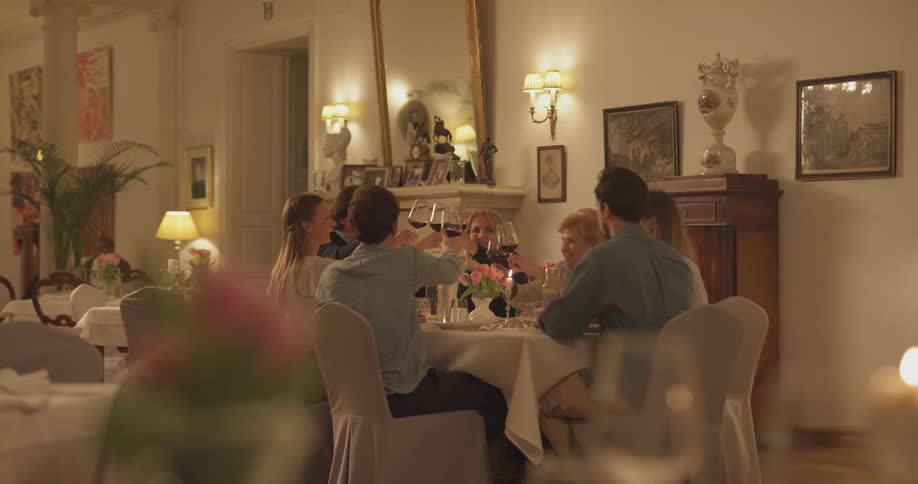 A group of people sitting at a dining table, use their glasses to cheers