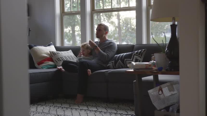 A man sitting on a couch eating popcorn with his daughter
