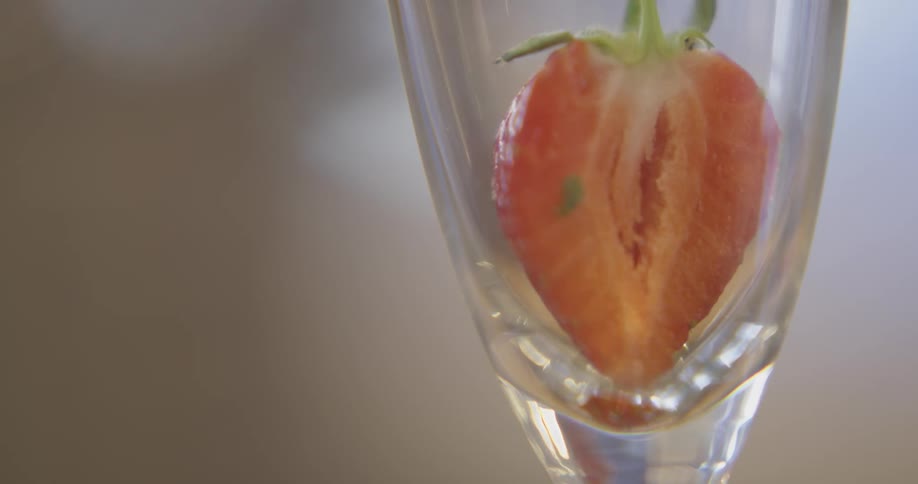 A strawberry is placed into a glass