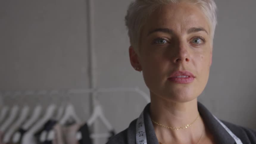 A woman has a fabric measuring tape around her neck