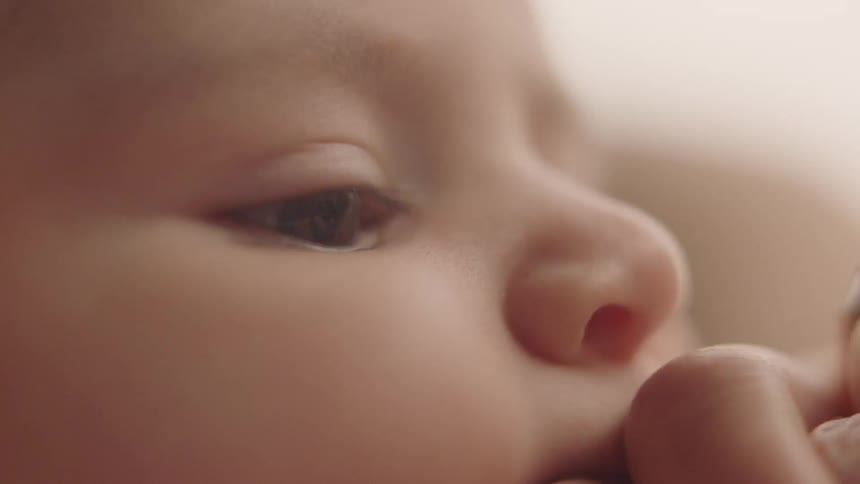 A baby chews on their hand