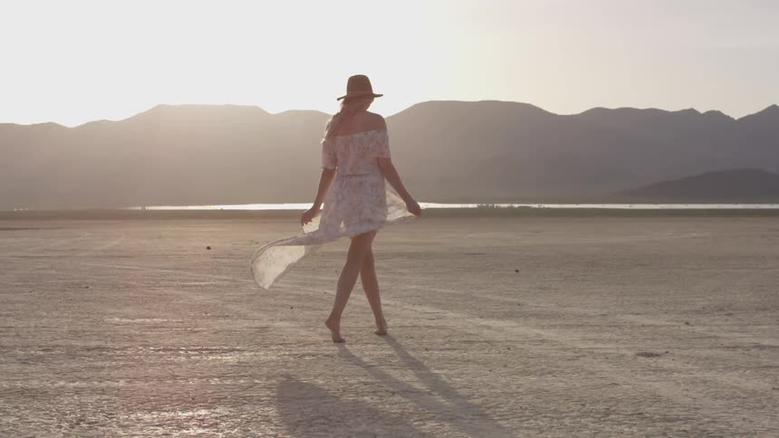 Woman walks on beach in light clothing