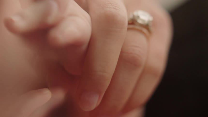 Woman with a very large diamond ring holding a babies hand