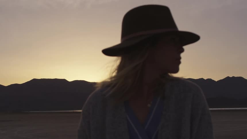 A woman turns her head away from the sunset she was looking at