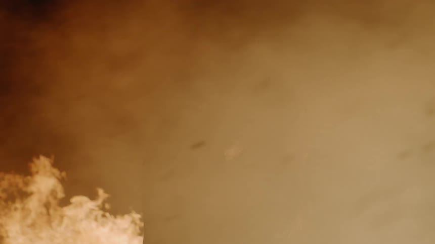 A man and woman kissing surrounded by fire and smoke