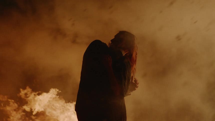 A man and women are kissing by a fire