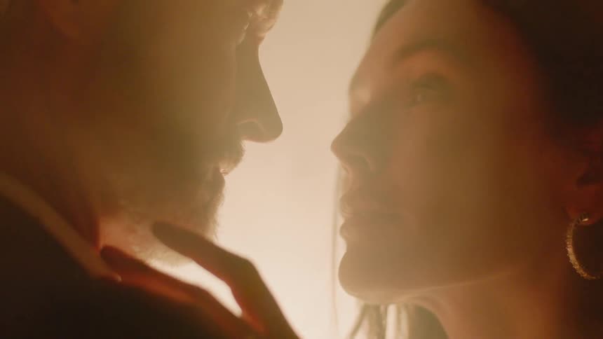 A man and a woman look in to each others eyes as fog passes in between them overly dramatic white gray hair and long black hair