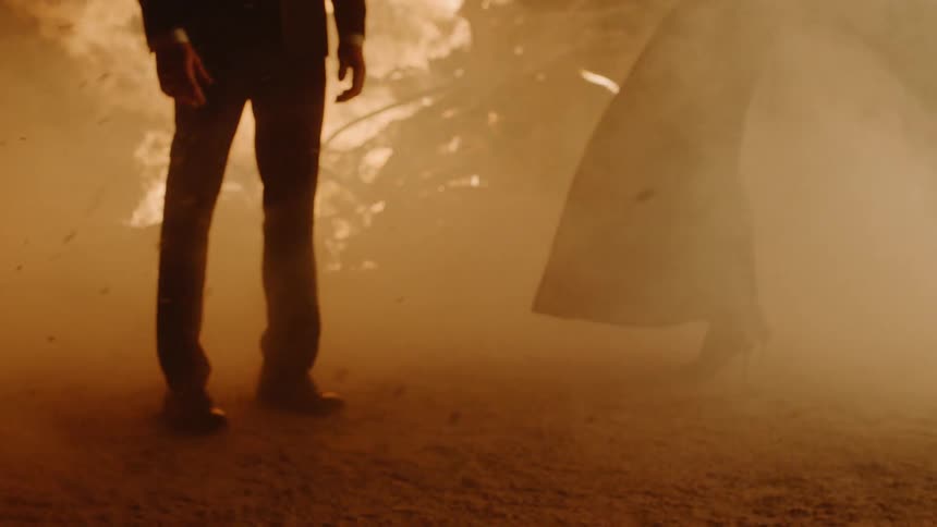 Ash and smoke from a large fire billow around a man and woman