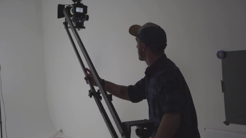 Camera operator moves camera towards woman sitting on a stool in a studio