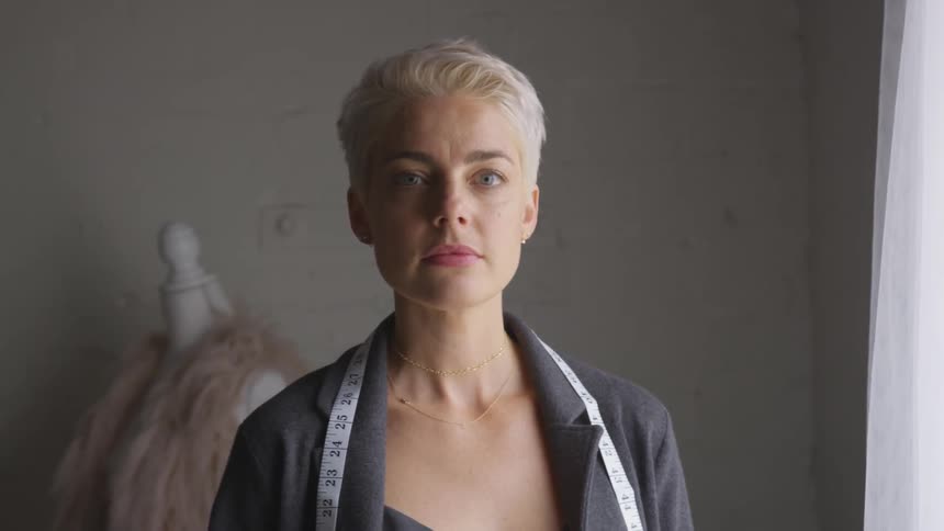 A fashion designer wears a measuring tape around her shoulders