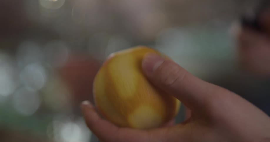Person peels an orange with a peeler