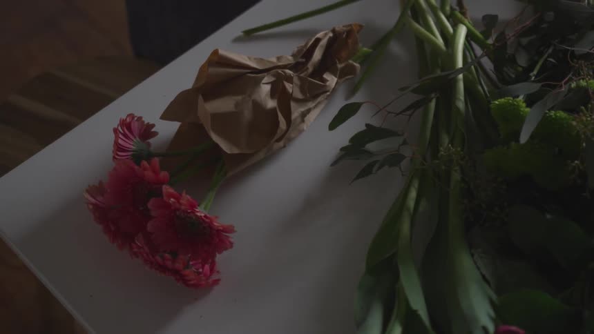 Flowers wrapped in paper lie on a florist table