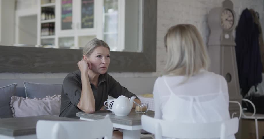 Two women talk over a pot of tea