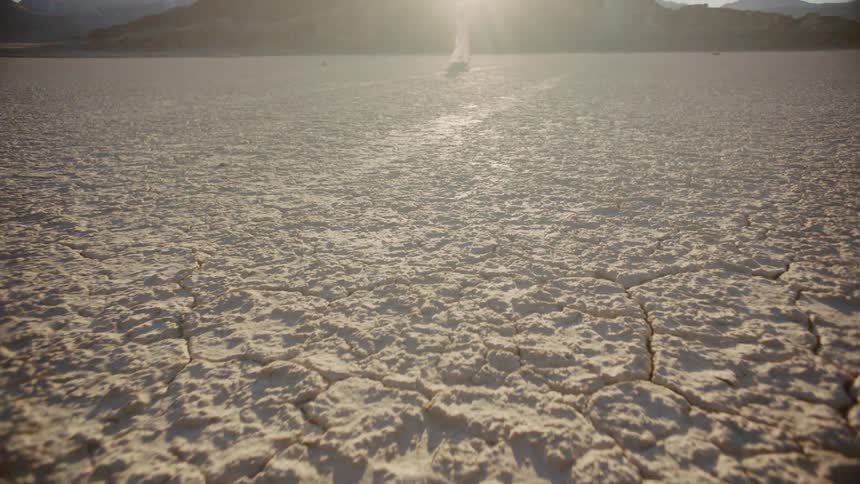 A woman stands in the back of the desert near a mountain