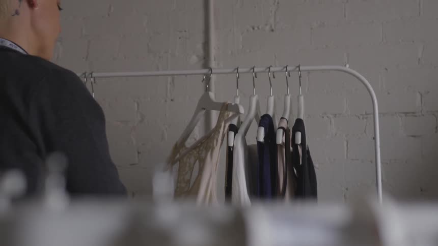 Woman looks through clothing hanging on a rack