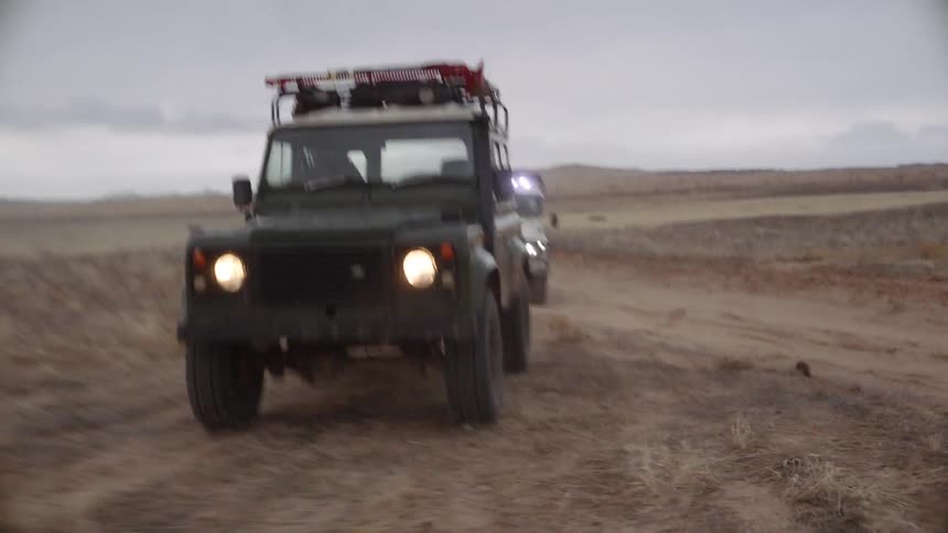 Two vehicles drive off the dirt road