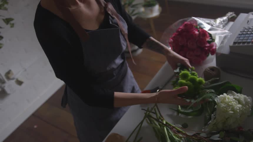 Woman is arranging a flower bouquet on a desk