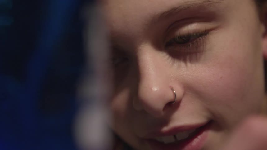 A girl with a nose ring smiles while watching a science experiment