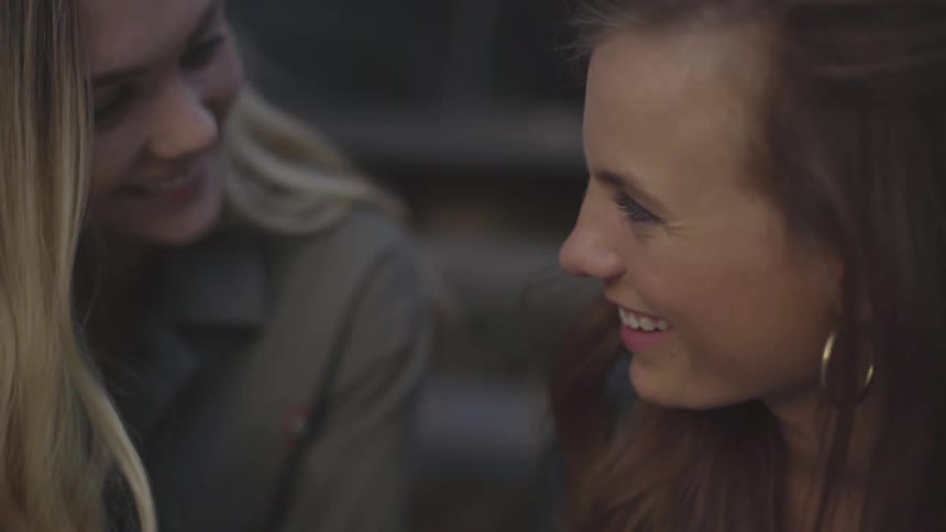 Two women looking at phone smile and laugh
