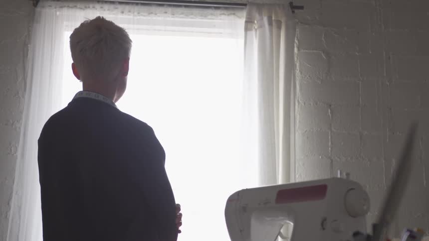 A person is staring out a window with their arms crossed