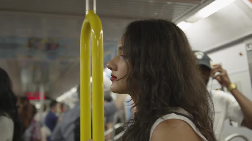 A woman standing up on a subway train